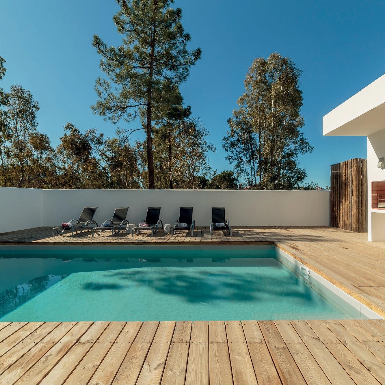 Terrasse en mélèze de couleur clair, avec une piscine et des lits de soleil