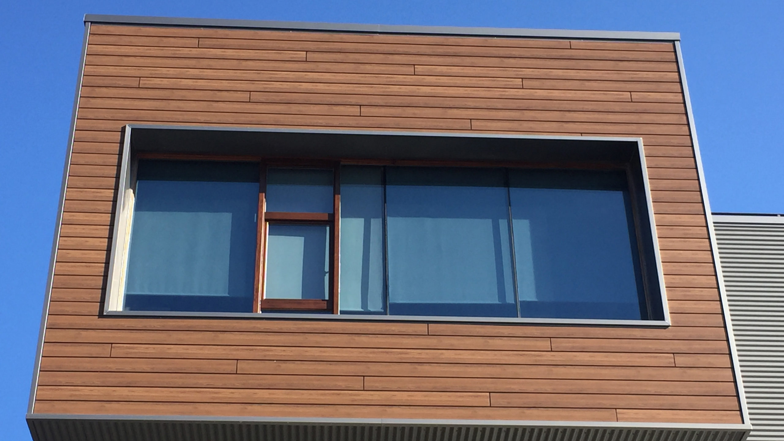 Bardage composite Werzalit Selekta REFINE en bois clair autour d'une grande fenêtre moderne