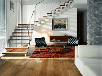 Salon avec parquet contrecollé marron clair, à droite un canapé blanc, un tapis rouge et des chaise en arrière plan, ainsi qu'un escalier.